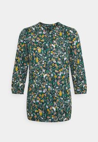 Blommig blus med trekvartslånga ärmar, med en mörkgrön bakgrund och ett mönster av gula, rosa och vita blommor. Rund halsringning.