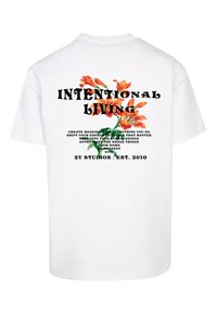 Hvit bomulls t-skjorte med et fargerikt blomsterdesign og teksten "INTENTIONAL LIVING" på baksiden med flere motiverende fraser under.