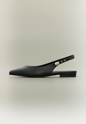 Chaussure plate slingback en cuir noir à bout pointu avec un petit talon et des détails métalliques sur la bride.