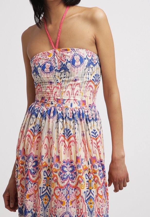 Robe sans bretelles avec un lien autour du cou, ornée d'un motif floral et géométrique coloré en bleu, rose, orange et jaune sur un tissu blanc.