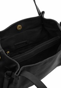 Zwart leren handtas interieur met een ritszak, meerdere compartimenten en een drukknopsluiting. Kenmerkt zich door een gladde textuur en een merklabel.