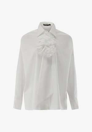 Weißes Langarmshirt mit strukturiertem Kragen und großem Stoffblumenverzierung auf der Vorderseite. Glatte Textur, lockere Passform und drapierte Gestaltung.