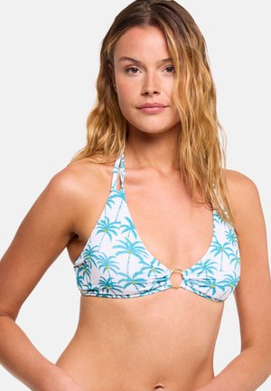 Mujer con cabello rubio ondulado que lleva un top de bikini blanco con estampado azul de palmeras y un detalle de anillo dorado en el centro delantero.