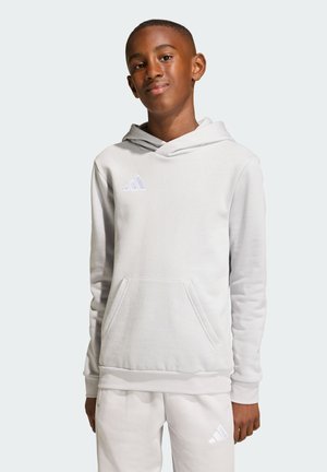 Vaaleanharmaa huppari, joka on valmistettu pehmeästä kankaasta, ja siinä on kengurun tasku sekä pieni valkoinen Adidas-logo rinnassa.