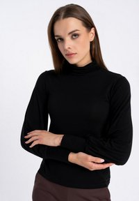 Czarna bluzka z długim rękawem, z półgolfem, dopasowany fason i marszczone rękawy. Miękka tkanina o gładkiej fakturze, styl minimalistyczny.