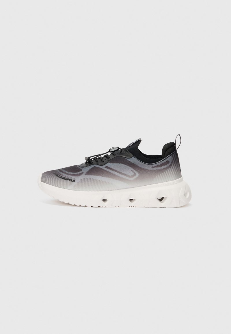 Sneaker atletiche con una tomaia che sfuma dal nero al grigio, caratterizzate da una finitura testurizzata, un sistema di lacci elastici e una suola bianca spessa con aperture.