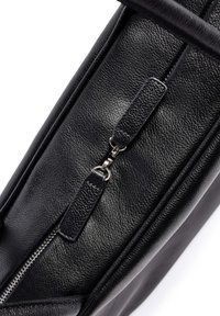 Borsa in pelle nera con superficie testurizzata, zip visibile con hardware in metallo e un design pulito e strutturato.