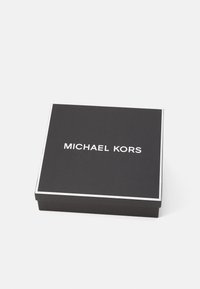 Scatola regalo quadrata nera con finitura testurizzata, con il logo bianco "MICHAEL KORS" centrato sulla parte superiore e un bordo bianco lungo i bordi.