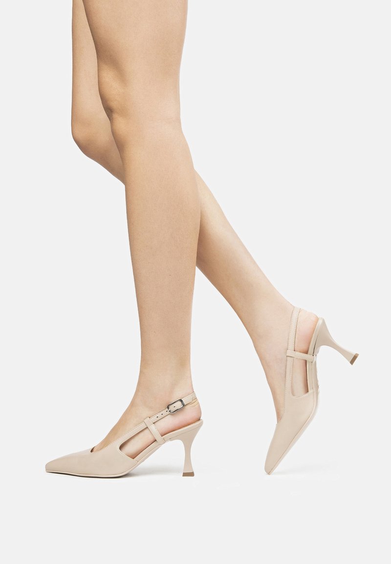 Tacchi beige slingback con punta affusolata, design a taglio e tacco sottile. Realizzati in materiale morbido con cinturino regolabile e piccolo dettaglio metallico.