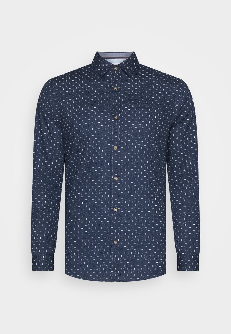 Chemise bleu marine à manches longues avec petit motif géométrique blanc et poche poitrine, présentée sur un fond clair uni.