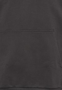 Dunkelgrauer Stoff mit einer horizontalen Naht über einer großen Fronttasche und sichtbaren Nähten auf der rechten Seite.