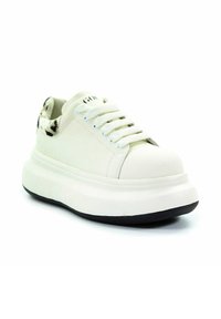 Białe sneakersy na platformie z grubą podeszwą, białymi sznurówkami i detalem w czarno-białą łatkę na kołnierzu pięty.