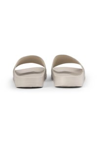 Ljust beige slide sandals med breda, formade öppna tår och fotvalvremmar. Tillverkade av ett glatt, flexibelt material med en texturerad sula.
