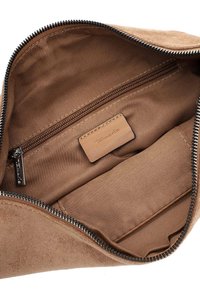Interieur van een bruine suede tas met een gladde, gestructureerde voering. Beschikt over een ritsvak en een leren label. Gestikte accenten langs de randen.