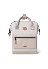 Sac à dos en toile beige clair avec une poche avant texturée, des accents en cuir, des fermetures éclair doubles et une poignée de transport supérieure. Logo circulaire au centre.