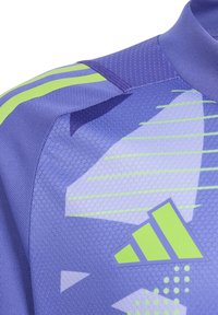 Paarse sportshirt met gestructureerde stof, grafische patronen en groene accenten. Inclusief opvallende branding op de linksonder.