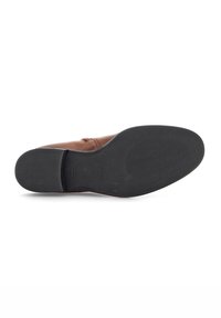Chaussure en cuir marron avec une tige lisse, une couture discrète et une semelle en caoutchouc noire flexible présentant un motif texturé pour l'adhérence.