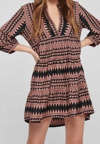 Black and pink patterned dress with a V-neck, three-quarter sleeves, elastic waist, and flared skirt featuring geometric designs.