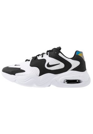 Biało-czarny sportowy sneaker z siateczkową cholewką, czarnym logiem Nike, grubą białą podeszwą, widoczną poduszką powietrzną w pięcie i czarnymi sznurówkami.