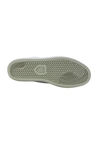 White sneaker sole with textured rubber, featuring a herringbone pattern and a central logo. Rounded shape and light green accent near edge.