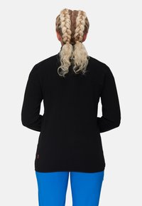 Black long-sleeve shirt with a high neckline and flat seams. Features a small orange label at the hem and smooth texture.
