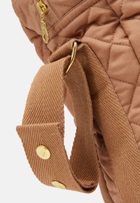 Sac marron matelassé en tissu texturé, avec une fermeture éclair et des accessoires dorés, et une large sangle sécurisée avec des boutons-pression dorés.