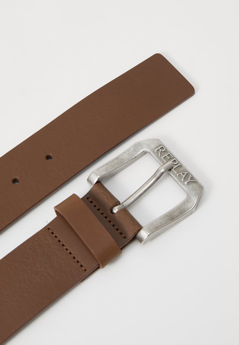 Ceinture en cuir marron avec une boucle en métal argenté gravée de "REPLAY". La ceinture a une texture lisse et plusieurs trous pour réglage.