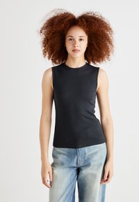 Black sleeveless ribbed tank top with a round neckline, paired with light blue loose-fit jeans. Smooth texture and fitted design.