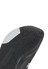 Semelle de chaussure de sport noire avec une finition texturée, présentant un accent blanc et un motif en chevrons pour une meilleure adhérence.