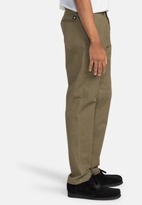 Licht olijfgroene broek gemaakt van katoen, met een rechte pijp. Gecombineerd met zwarte nubuck moccasinschoenen.