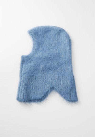 Lichtblauwe, fuzzy muts met een unieke vorm, met een opening aan de zijkant en gemêleerde brei-details. Zacht, warm materiaal.