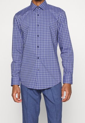 Camicia a maniche lunghe a quadretti blu e bianchi con colletto a bottoni e bottoni neri. Presenta un orlo curvo e polsini aderenti.