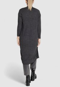 Abito lungo grigio scuro lavorato a maglia con texture a coste, fessure laterali e maniche raglan, abbinato a pantaloni grigi e stivali platform neri.