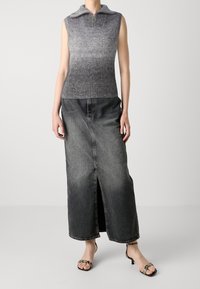 Ärmelloses graues Ombre-Stricktop mit Reißverschluss und Kragen, kombiniert mit einem langen, ausgebleichten schwarzen Jeansrock mit Schlitz vorne und offenen Schuhen.