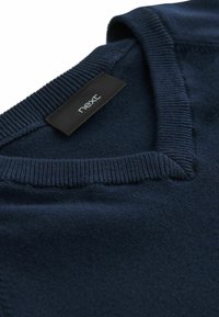 Pullover blu navy con scollatura a V, colletto a coste e un'etichetta con la scritta "next". Realizzato in tessuto morbido con una superficie liscia.