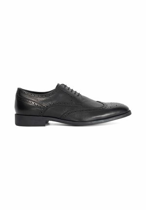 Chaussure brogue pour homme en cuir noir avec design à bout ailé, détails perforés, talon bas et fermeture à lacets, vue de profil latéral.