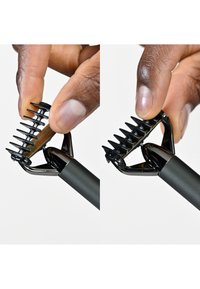 Svart grooming-verktøy med kamfestebit, utstyrt med teksturert håndtak og flere pigger. Viser to bruksposisjoner.
