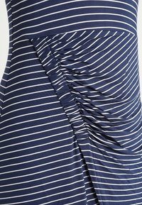 Granatowa sukienka w białe poziome paseczki, z marszczeniem po boku. Wykonana z miękkiego, elastycznego materiału dla zapewnienia komfortu.