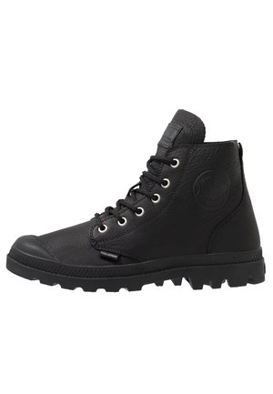 Black high-top boots made of textured leather, featuring eight eyelets, a rubber toe cap, and a rugged sole with distinct tread pattern.