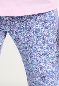 Bomullsleggings med blommönster i pastellfärger, med en ljusblå botten och små lila, rosa och gula blommor. Elastisk midjeresår.