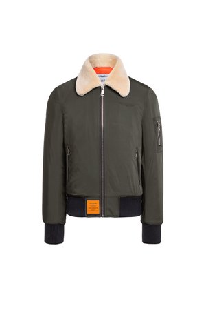 Giacca bomber verde scuro con colletto in pelliccia sintetica, chiusura con zip, polsini a coste e un'etichetta arancione all'orlo. Texture liscia, design classico.