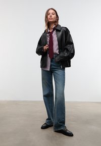 Svart läderoversized jacka, vit och burgundy randig skjorta, mörk burgundy slips, ljusblå vid jeans, blanka svarta loafers.