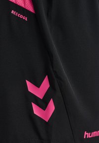 Tejido negro con el texto "BEECOOL" en rosa, dos flechas en forma de cheurón hacia abajo y el logo "hummel", probablemente parte de una prenda deportiva.