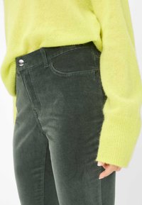 Grønne kordfløjlsbukser med slim fit, der har en frontlomme, metalknap og en lysegul oversized striktrøje.