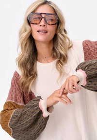 Sweter w kolorze kremowym z wzorzystymi balonowymi rękawami w kolorze burgundowym, złotym i niebieskim. Teksturowana tkanina z falbaniastymi mankietami w kolorze różowym i srebrnym.