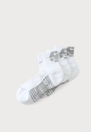 Vier Paar weiße Knöchelsocken mit grauen Akzenten und sichtbarem Nike-Logo am Bündchen und an der Fußsohle, in einer Reihe angeordnet.