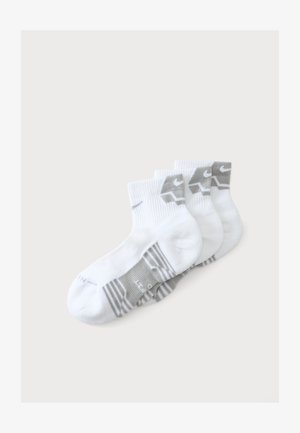 Quatre paires de chaussettes basses blanches avec des touches grises et un logo Nike visible sur le bord et la semelle, disposées en rangée.