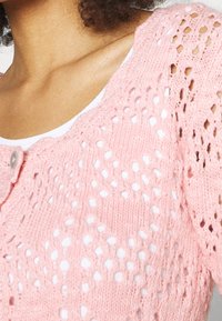 Hellrosa gestrickte Strickjacke mit einem filigranen Muster, Rundhalsausschnitt und einem einzigen Knopfverschluss vorne.