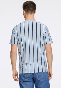 Ljusblå t-shirt med kort ärm och vertikala svarta och vita ränder. Har rund halsringning och en avslappnad passform. Tillverkad av mjuk bomullsblandning.