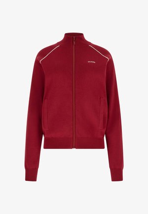 Rode sweater met ritssluiting, geribbelde boorden en zoom, witte bies op de schouders en een klein wit "GUESS"-logo op de linkerborst.